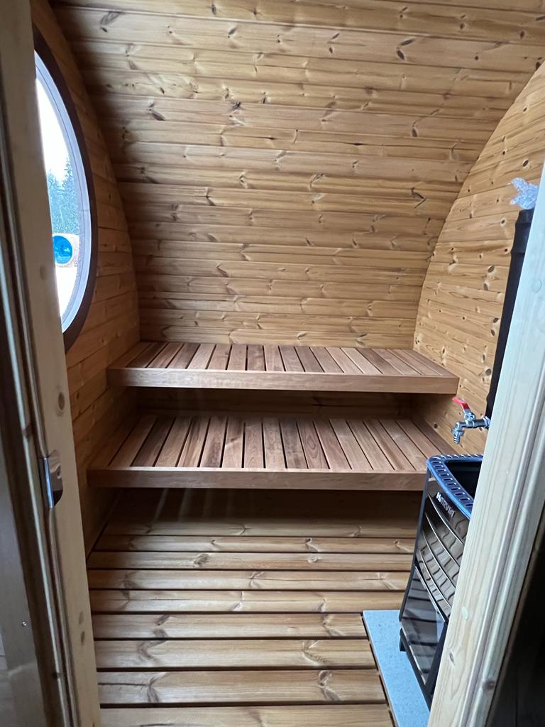 Hobbit 195 outdoor sauna with circular window and curved design.