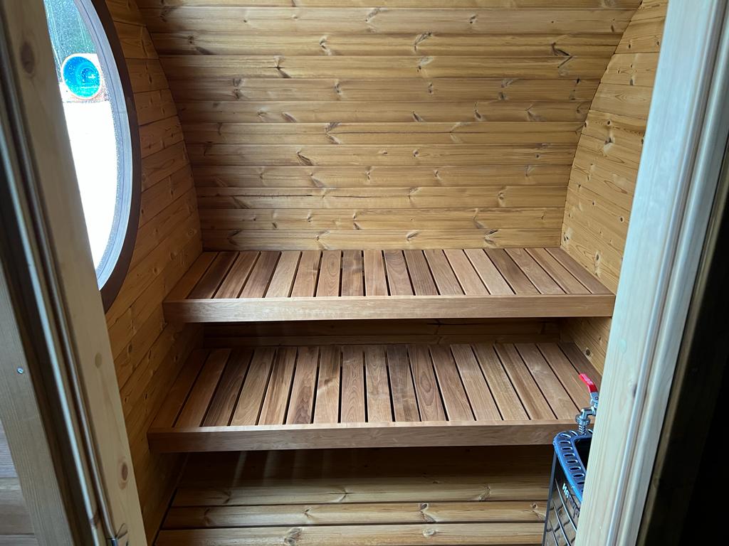 Hobbit 195 outdoor sauna with circular window and shelf.