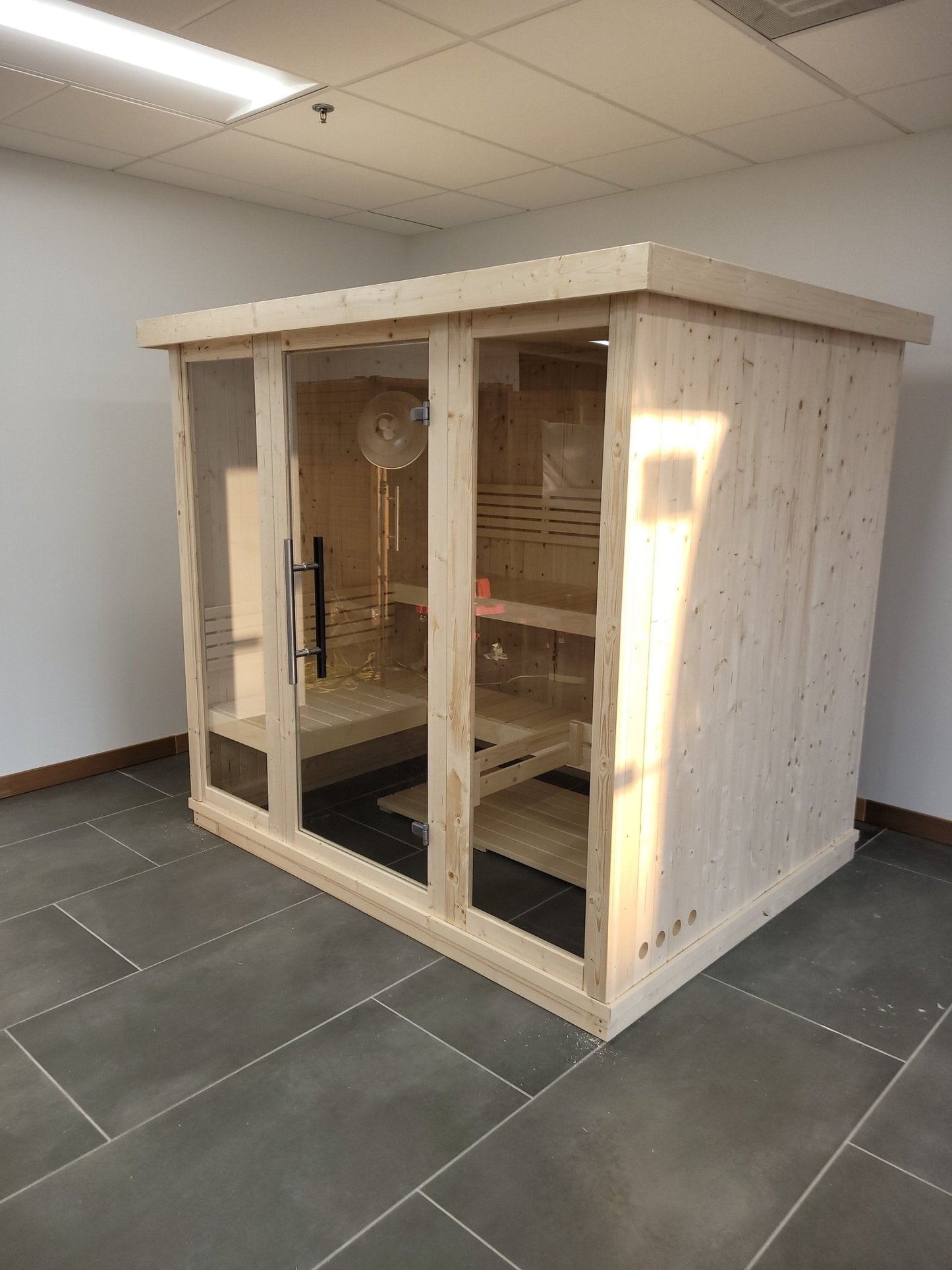 Grande sauna interna con porte di vetro in camera.