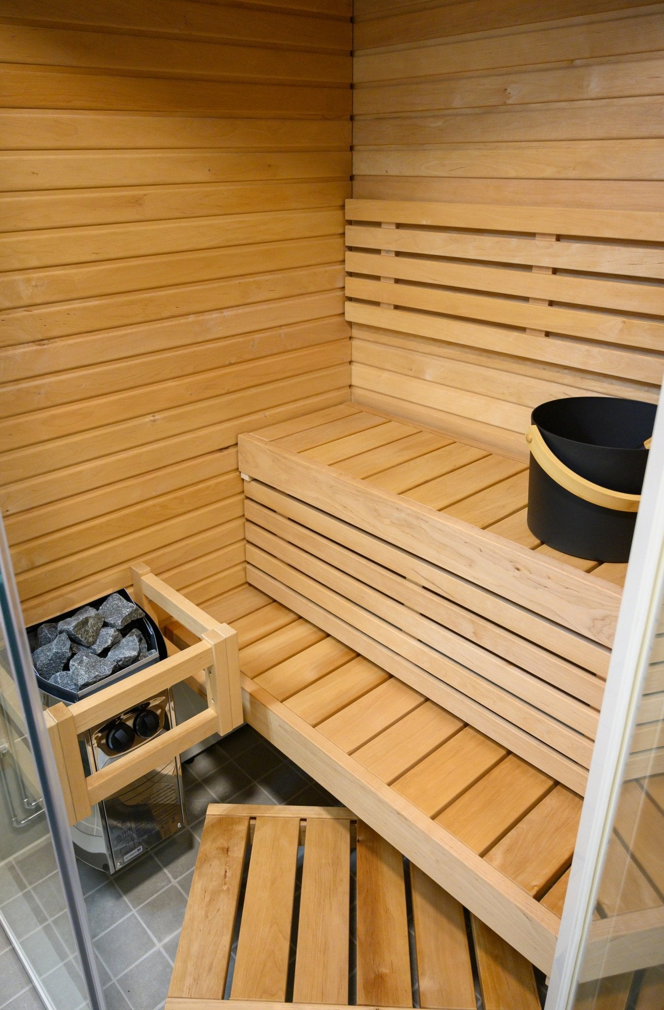 Sirius Corner sauna with bucket and visible stones.