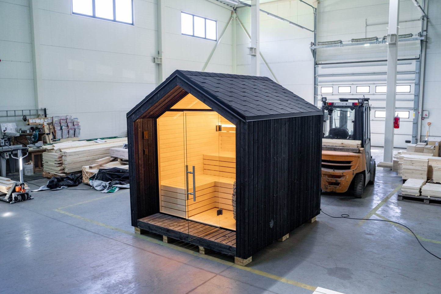 Sauna exterior Lumi con puerta de cristal y luz interior.