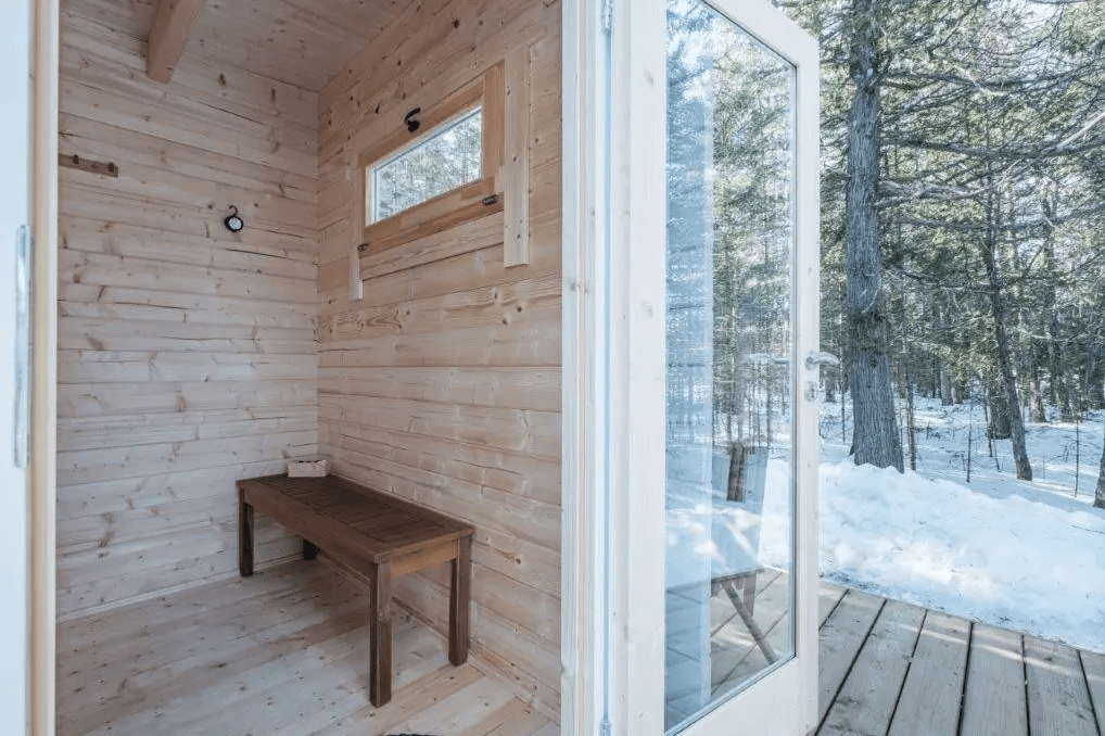 Sauna exterior Nordica con banco y puerta de cristal.