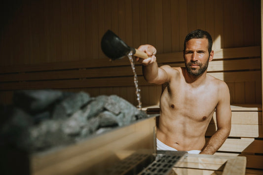 Homem a deitar água nas pedras quentes da sauna.