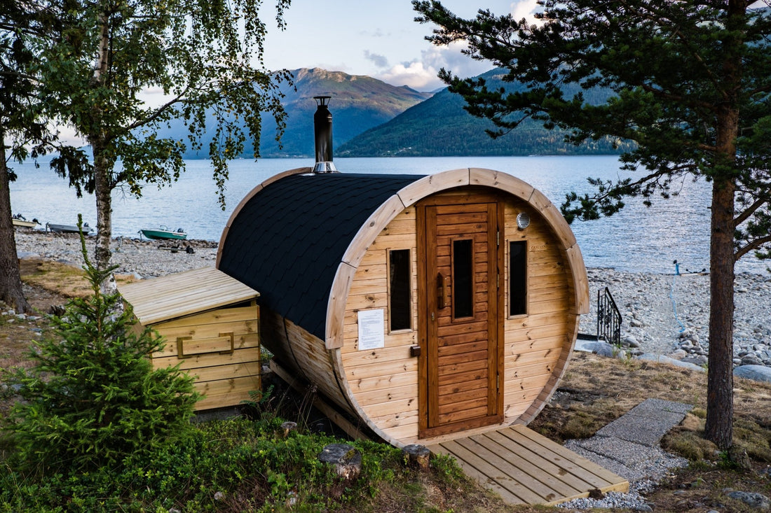 Sauna de barril com telhado preto à beira de um lago.