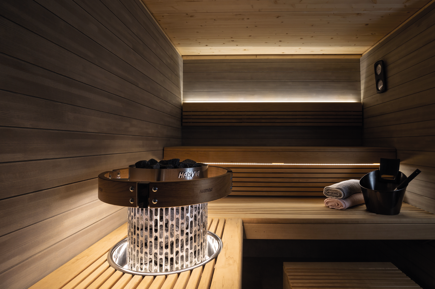 Conjunto de Iluminação LED Harvia em sauna com pedras e balde.