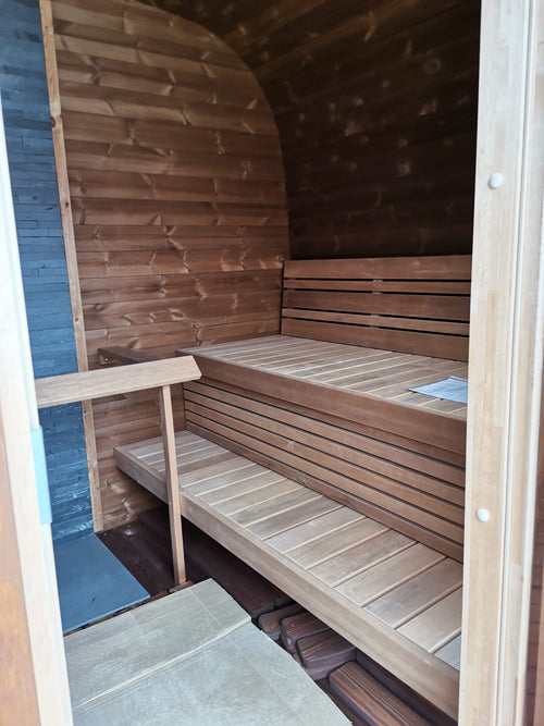 Cubus outdoor sauna with wooden benches indoors.