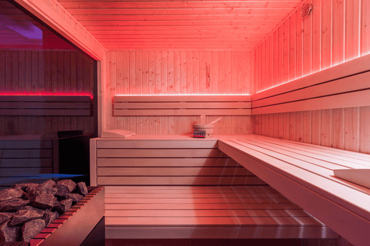 Sauna esterna alpina isolata con luce rossa e panca interna.