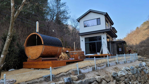 Outdoor sauna Barrel 250 in garden with wooden barrel.