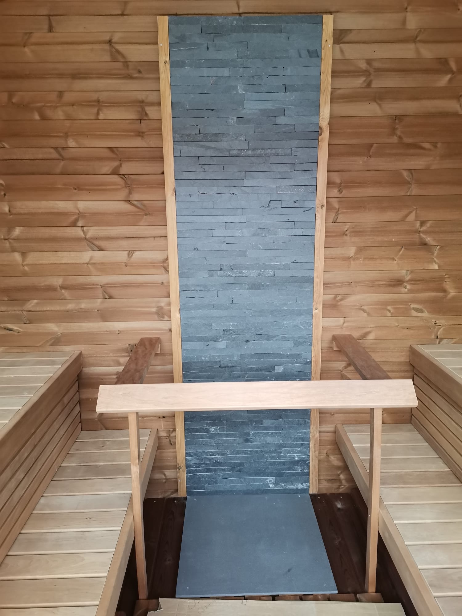 Sauna Saunamo Cubus com parede de pedra e bancos em madeira.